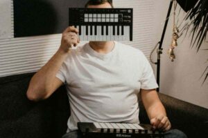 uomo con davanti alla faccia una tastiera midi