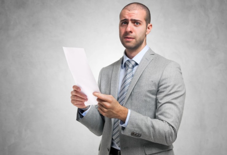 uomo con un foglio in mano con espressione preoccupata