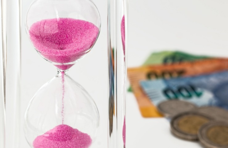 clessidra e dietro banconote e monete di euro