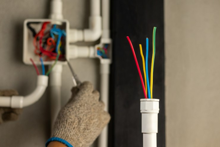 un elettricista che sta lavorando con dei cavi elettrici a muro