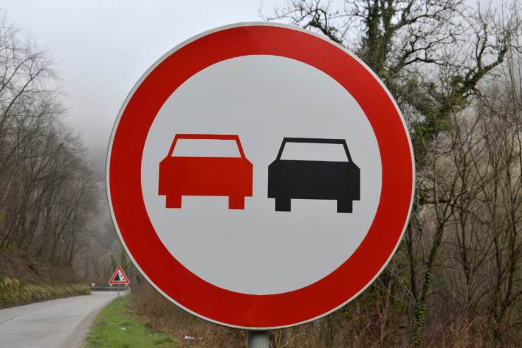 una foto di un segnale stradale che vieta il sorpasso